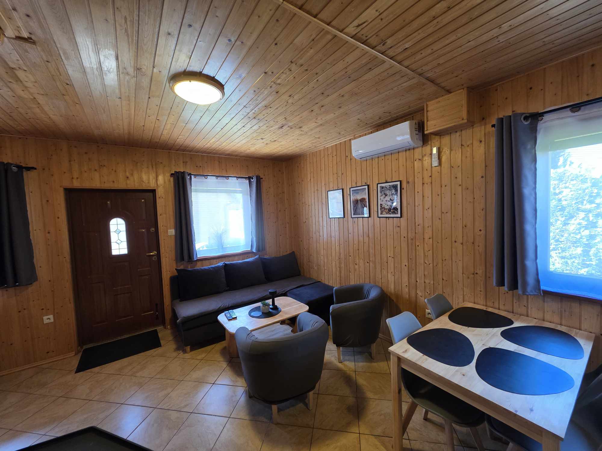 Salon z klimatyzacją, sofą i jadalnią w Aurum Domki