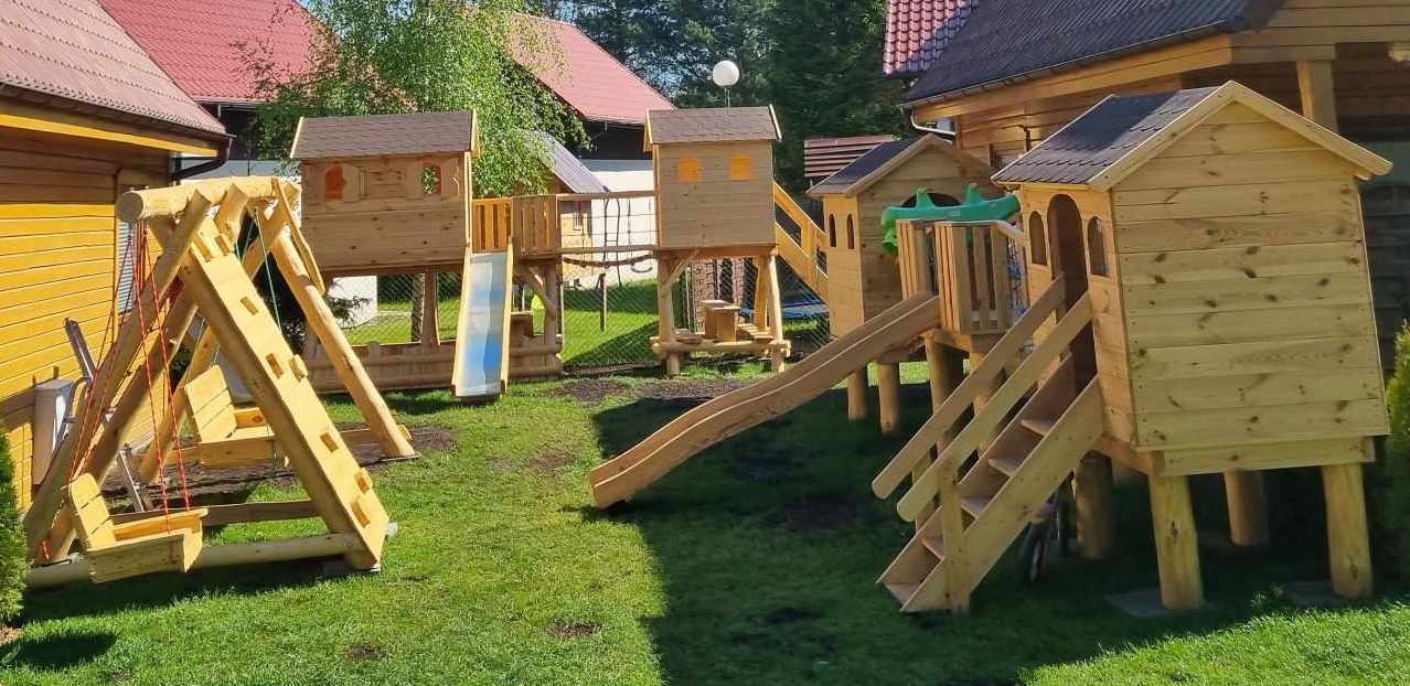 Drewniane domki do zabawy, zjeżdżalnie i huśtawki na terenie Aurum Domki